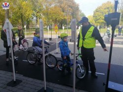 policjant prezentuje dzieciom miasteczko ruchu drogowego