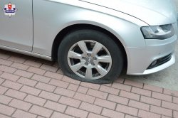 fragment stojącego samochodu z widoczną uszkodzoną oponą