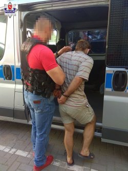 policjant wprowadza do radiowozu zatrzymanego mężczyznę