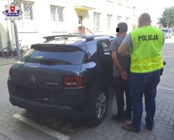 policjant doprowadza zatrzymanego mężczyznę